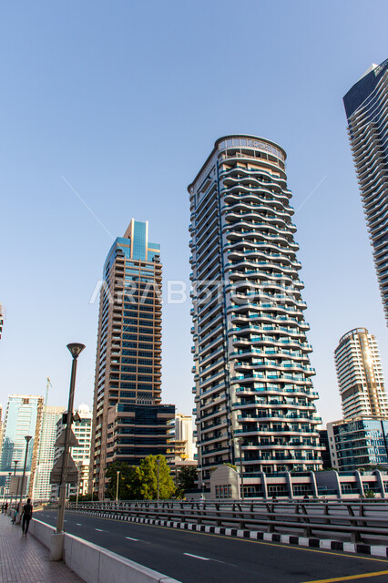 الهندسة الفنية المعمارية على الطراز الحديث للمباني وناطحات السحاب, الأبراج المطلة على مرسى اليخوت في مارينا دبي على ساحل الخليج العربي, معالم سياحية مشهورة وقت النهار, الإهتمام بتشجير الأشجار والنباتات الخضراء في الامارات العربية المتحدة