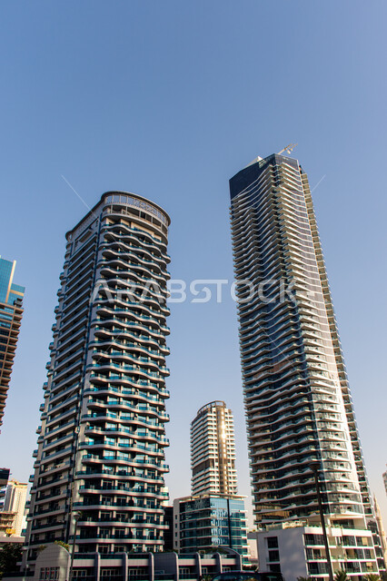الهندسة الفنية المعمارية على الطراز الحديث للمباني وناطحات السحاب, الأبراج المطلة على مرسى اليخوت في مارينا دبي على ساحل الخليج العربي, معالم سياحية مشهورة وقت النهار, الإهتمام بتشجير الأشجار والنباتات الخضراء في الامارات العربية المتحدة