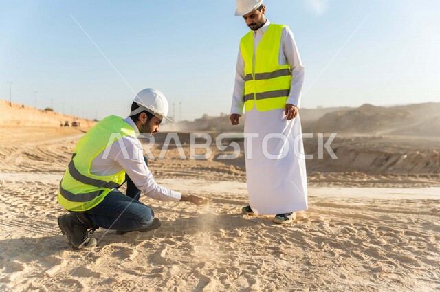 مقاول ومشرف العمل يرتديان خوذة وسترة خاصة بالعمل، عربيان خليجيان سعوديان يقومان باختبار جودة الرمل بموقع العمل  ، التحقق من وجود الطين الزائد ،اشراف ومتابعة العمل ، متابعة استراتيجية المشروع