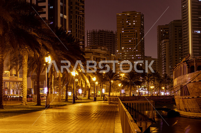 Architectural engineering of residential and commercial facilities overlooking the waterfront, towers and skyscrapers illuminated at night on the Khalid Lagoon Corniche in Sharjah, famous landmarks and tourist places