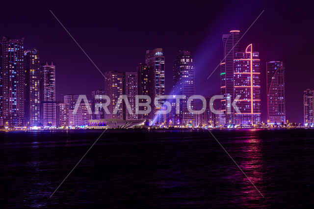 الفن الهندسي المعماري للأبراج وناطحات السحاب المضيئة ليلا المطلة على الخليج العربي، المعالم السياحية المشهورة، اماكن جذب واستقطاب السياح، اطلالة على الوجهة البحرية، كورنيش بحيرة خالد في مدينة الشارقة بالامارات العربية المتحدة