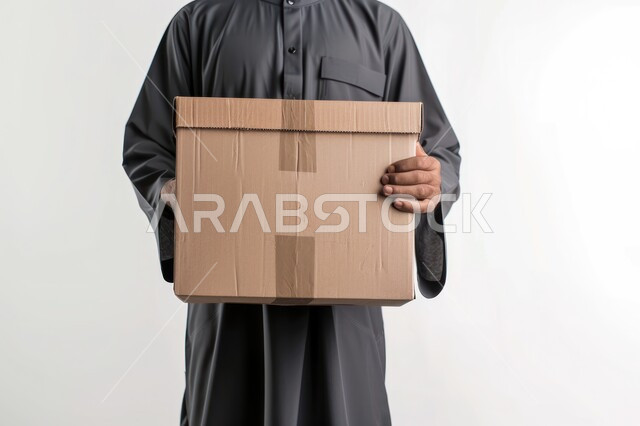 مفهوم التسوق الالكتروني, خدمة توصيل الطلبات للزبائن, خدمات الشحن الآمنة و الموثوقة في السعودية, بورتريه مقرب لرجل عربي خليجي سعودي يرتدي الثوب التقليدي يحمل بيديه صندوق, خلفية بيضاء