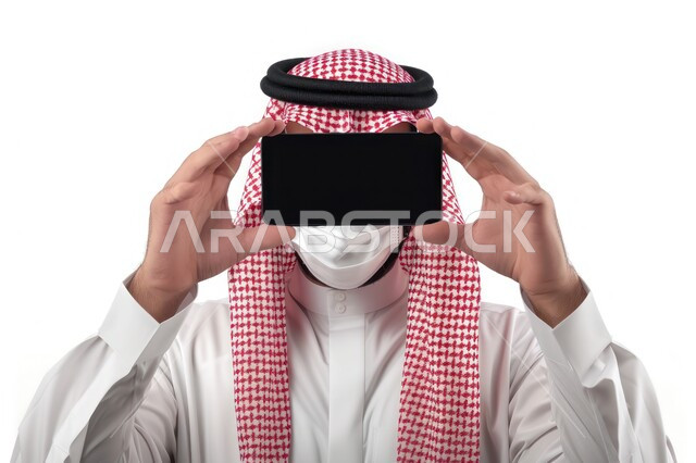 عرض شاشة سوداء فارغة، صورة أمامية لشاب عربي خليجي سعودي يرتدي الزي السعودي التقليدي يمسك بيده الهاتف المحمول ويضعه أمام وجهه
