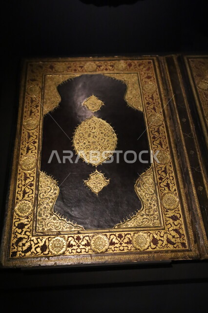 غلاف لكتاب ديني مزخرف بزخارف ونقوش باللون الذهبي، متحف بينالي للفنون والثقافة الإسلامية بمدينة جدة في المملكة العربية السعودية، عرض الأعمال الفنية الدينية المعاصرة، أماكن جذب واستقطاب الزائرين