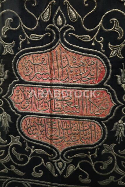 عرض لكسوة الكعبة المطرزة بخيوط ذهبية وفضية، التعرف على ثقافة وتاريخ الأراضي المقدسة، متحف بينالي للفنون الإسلامية في جدة بالمملكة العربية السعودية, التحف والمقتنيات الدينية الأثرية المميزة، الستارة الحريرية السوداء لباب الكعبة المنقوشة بآيات من القرآن الكريم