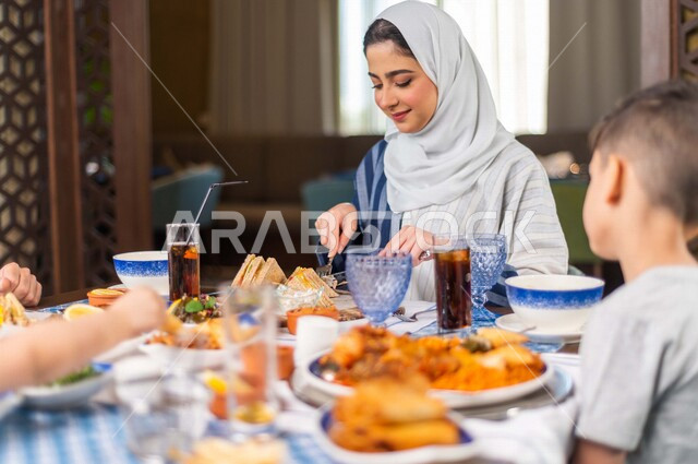 عائلة عربية خليجية سعودية تجلس في المطعم ، عائلة خليجية سعودية مستمتعة بتناول الافطار الرمضاني الشهي ، سفرة رمضانية مليئة بأشهى المأكولات والمشروبات ، قضاء وقت ممتع ، رمضان كريم