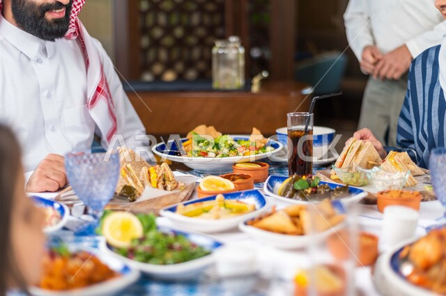 تصوير مقرب لسفرة رمضانية مليئة بأشهى المأكولات والمشروبات ، عائلة عربية خليجية سعودية تتناول الافطار في المطعم ، قضاء وقت ممتع ، رمضان كريم