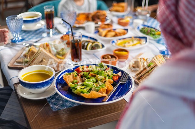 Close-up photography of a Ramadan trip filled with delicious food and drinks, a Saudi Arabian Gulf family eating breakfast in the restaurant, having a good time, Ramadan Kareem