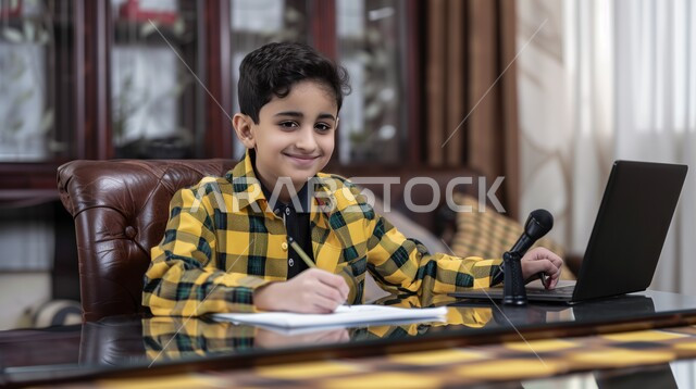 طالب يجلس على طاولة الدارسة ويمسك بيده القلم ويضع الدفتر امامه, الاجتهاد والمشاركة التطوعية من خلال دورات التعلم عن بعد، بورتريه لتلميذ عربي خليجي سعودي, يحضر دروسه عن طريق الكمبيوتر