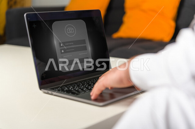 صورة مقربة ليد رجل خليجي سعودي ، يستخدم جهاز الحاسوب المحمول يعمل على تأمين الحسابات ،الأمان و الخصوصية  عند تصفح تطبيقات السوشال ميديا .