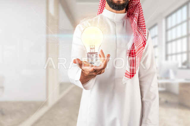 A close-up of the hand of a Saudi Gulf man, holding a light bulb in his hands surrounded by a spider web with hologram technology, vision to achieve achievements and innovations, using the 3D hologram feature.