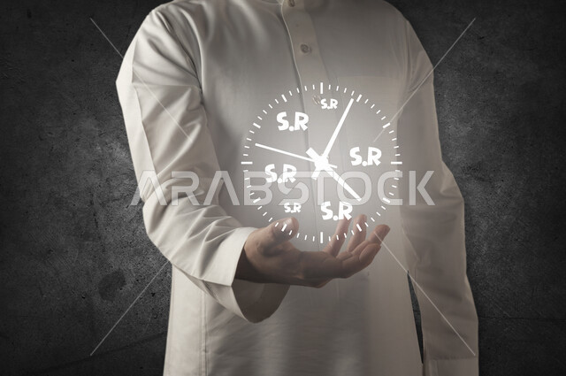 صورة مقربة لرجل عربي خليجي يحمل بين يديه ساعة تحتوي على رمز اختصار الريال السعودي بتقنية الهولوجرام ، استخدام خاصية الهولوجرام ثلاثية الابعاد .