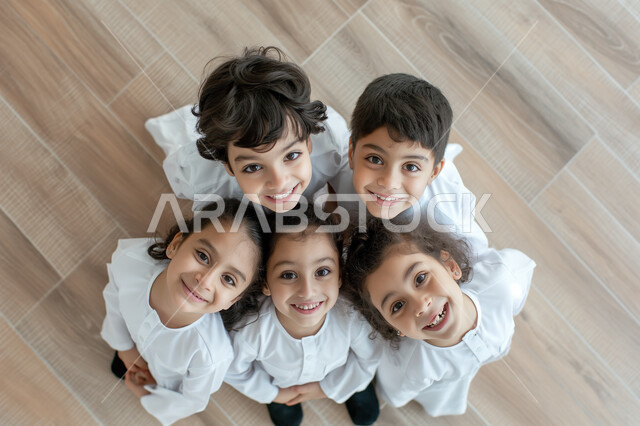 استقبال العام الدراسي الجديد بحماس، مفهوم التعلم في المملكة العربية السعودية، صورة علوية عامودية لمجموعة تلاميذ عرب خليجيين سعوديين مبتسمين يتظرون الى الكاميرا بتعابير السرور والسعادة، التربية والتعليم بالمناهج المقررة للطلاب
