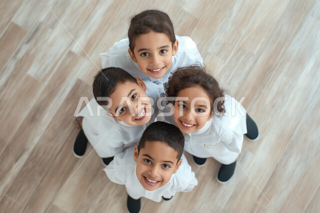 مفهوم التعلم في المملكة العربية السعودية، استقبال العام الدراسي الجديد بحماس، صورة علوية عامودية لمجموعة تلاميذ عرب خليجيين سعوديين مبتسمين يتظرون الى الكاميرا بتعابير السرور والسعادة، التربية والتعليم بالمناهج المقررة للطلاب