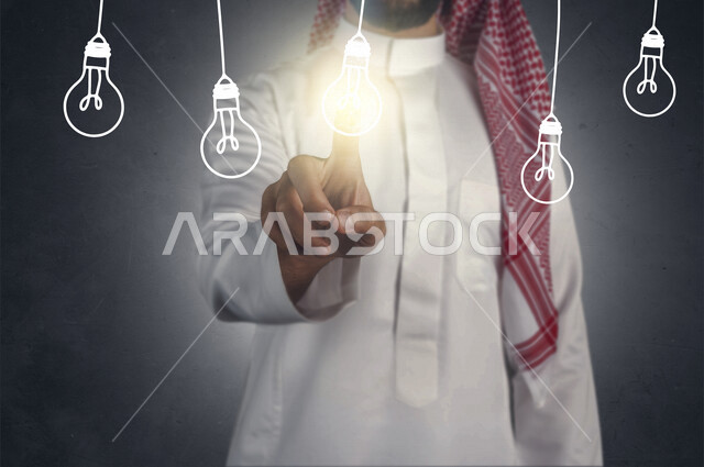 صورة مقربة ليد رجل خليجي سعودي ، يضغط بأصبعه على مصباح مضيئ ضمن مجموعة مصابيح مضيئة معلقة بتقنية الهولوجرام ، استخدام خاصية الهولجرام ثلاثية الأبعاد .