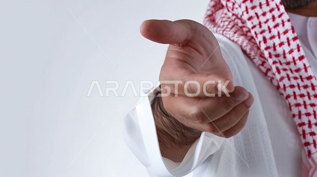 Pointing towards something and specifying a target, hand gesture indicating this place (here), close-up portrait of a Saudi Arabian Gulf man wearing traditional thobe pointing with index finger to a specific place, white background