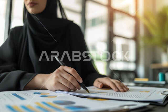 جمع بيانات البورصه وسوق الأسهم, مفهوم الدقة والتركيز في انجاز المعاملات، تحقيق الاهداف المالية للشركة، صورة مقربة لسيدة أعمال عربية خليجية سعودية تقوم بدراسة الأرباح، دراسة و تحليل الاحصائيات و الرسوم البيانية, دمج التكنولوجيا مع العمل.