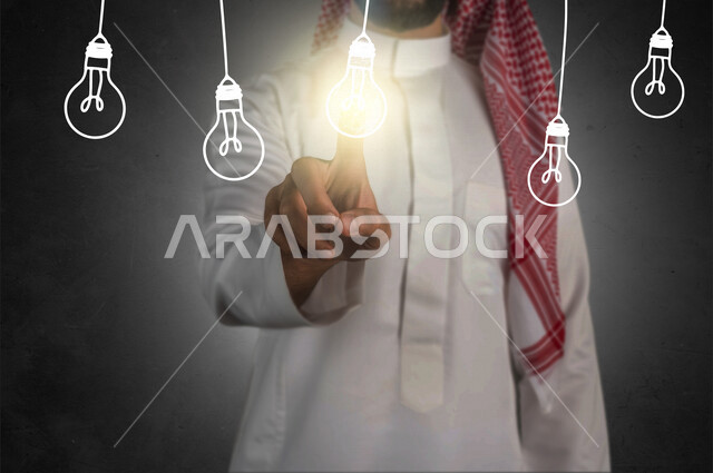 A close-up of the hand of a Saudi Gulf man pressing his finger on a lighted lamp within a group of illuminated hanging lights using hologram technology, using the hologram feature.