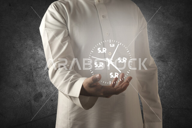 صورة مقربة لرجل عربي خليجي يحمل بين يديه ساعة تحتوي على رمز اختصار الريال السعودي بتقنية الهولوجرام ، استخدام خاصية الهولوجرام ثلاثية الابعاد .