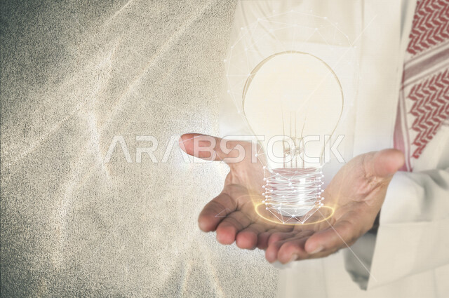 صورة مقربة ليد رجل خليجي سعودي ، يحمل بين يديه مصباح ضوئي محاطة بشبكة عنكبوتية بتقنية الهولوجرام ، الرؤية لتحقيق الانجازات و الابتكارات ، استخدام خاصية الهولجرام ثلاثية الأبعاد .