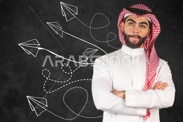صورة مقربة لرجل ريادي أعمال عربي خليجي سعودي أمام خلفية تحتوي على مجموعة من الطائرات الورقية المتطايرة بإيماءات وجه ويدين تدل عالتفكير و تطوير الأفكار ، مهارة الابداع .