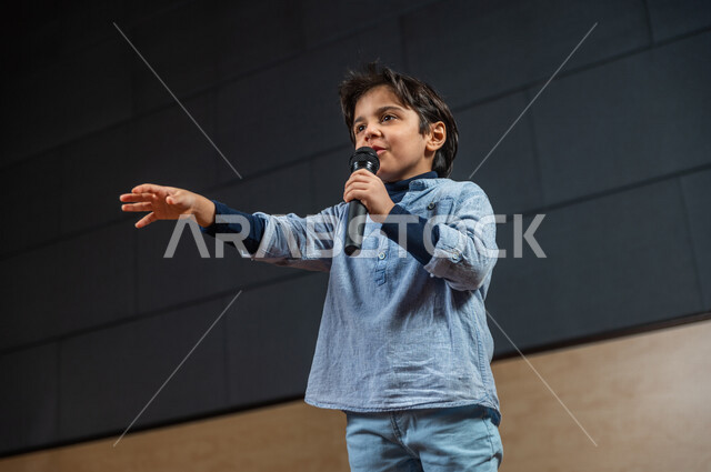  طفل سعودي خليجي على خشبة المسرح ،  تقديم العروضات المسرحية ، نشيد وغناء ، اداء تمثيلي ، ايماءات وجه و يدين مختلفة ، الفن المسرحي 