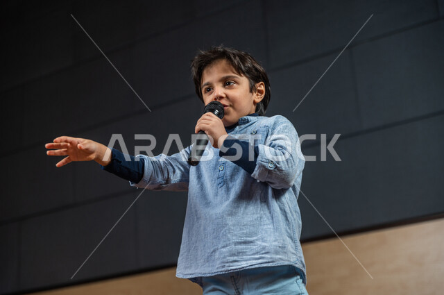  طفل سعودي خليجي على خشبة المسرح ،  تقديم العروضات المسرحية ، نشيد وغناء ، اداء تمثيلي ، ايماءات وجه و يدين مختلفة ، الفن المسرحي 