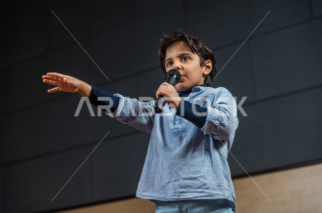  طفل سعودي خليجي على خشبة المسرح ،  تقديم العروضات المسرحية ، نشيد وغناء ، اداء تمثيلي ، ايماءات وجه و يدين مختلفة ، الفن المسرحي 