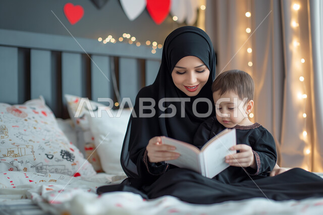 تقديم كروت التهنئة والهدايا الأعياد والمناسبات، إحياء ذكرى عيد الأم، مفهوم احترام وتقدير الوالدين، امرأة عربية خليجية سعودية محجبة ترتدي العباءة التقليدية تمسك بيدها كرت معايدة قدمه لها طفلتها الصغيرة، أم تحتضن ابنتها في جو مليء بالحب والعطف والحنان