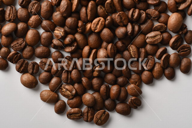 حبوب البن (بذرة نبات القهوة) نوع من أنواع المشروبات المنشطة ذهنياً , بذور البن المحمصة ,  بذور البن الطازجة الطبيعية  , خلفية بيضاء