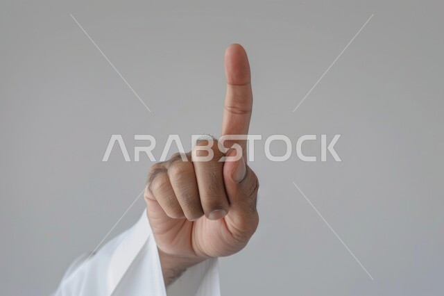 Expressions of certainty and specificity, pointing to something, close-up portrait of a Saudi Arabian Gulf man in traditional dress pointing with index finger to select, gray background