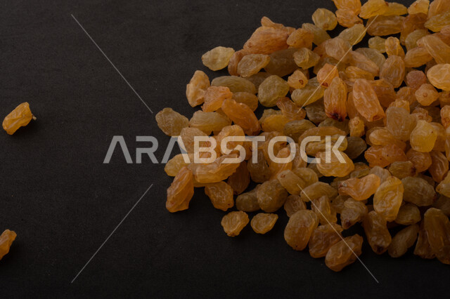 الزبيب (العنب المجفف) نوع من أنواع الفواكهة المجففة , صورة مقربة للزبيب المجفف , فواكة مجففة صحية ولذيذة , عنصر غذائي مفيد للصحة , خلفية سوداء