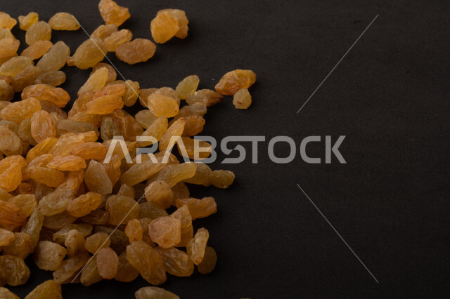 الزبيب (العنب المجفف) نوع من أنواع الفواكهة المجففة , صورة مقربة للزبيب المجفف , فواكة مجففة صحية ولذيذة , عنصر غذائي مفيد للصحة , خلفية سوداء