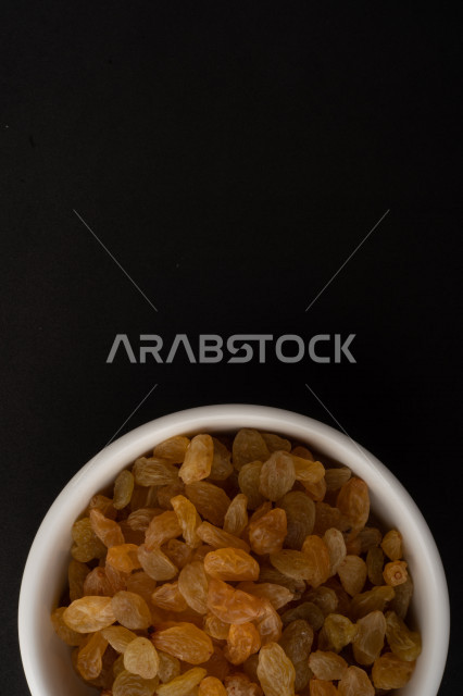 الزبيب (العنب المجفف) نوع من أنواع الفواكهة المجففة , صورة مقربة للزبيب المجفف , فواكة مجففة صحية ولذيذة , عنصر غذائي مفيد للصحة , خلفية سوداء