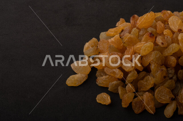 الزبيب (العنب المجفف) نوع من أنواع الفواكهة المجففة , صورة مقربة للزبيب المجفف , فواكة مجففة صحية ولذيذة , عنصر غذائي مفيد للصحة , خلفية سوداء