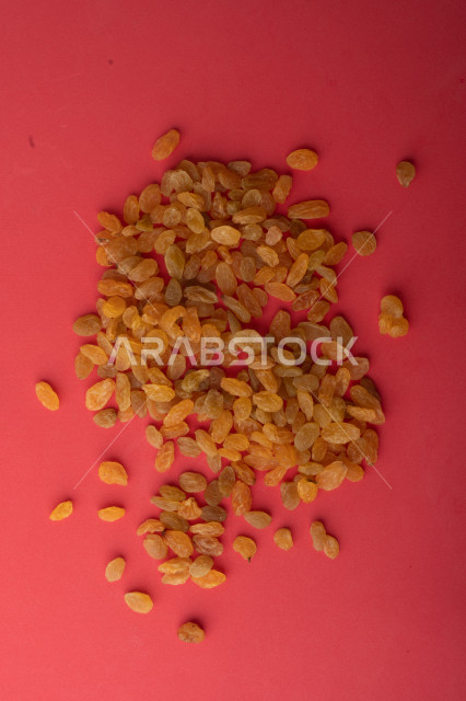 الزبيب (العنب المجفف) نوع من أنواع الفواكهة المجففة , صورة مقربة للزبيب المجفف , فواكة مجففة صحية ولذيذة , عنصر غذائي مفيد للصحة, خلفية ملونة باللون الزهري
