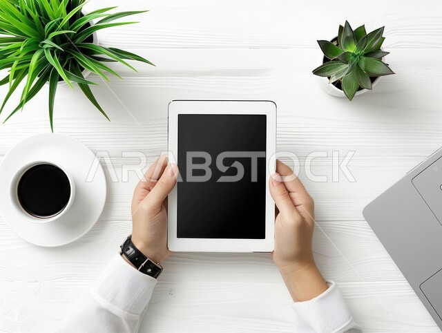 Electronic development and technological growth, top view of the hands of an Arab Gulf man holding a tablet device while completing work and tasks in the office, Saudi office jobs and professions, use of modern and advanced technologies, white background