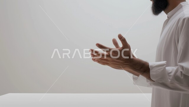 التقرب الى الله تعالى من خلال الاجتهاد في العبادة، صورة مقربة لرجل عربي سعودي خليجي يرتدي الزي التقليدي يرفع يديه للدعاء والاستغفار، طلب العون والحمد والشكر، ايماءات يدين تدل على التضرع والرجوع الى الله