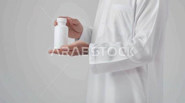 أخذ جرعات الأدوية بشكل صحيح, أدوية لمعالجة الحالات المرضية، استخدام العلاج الطبي اللازم، الوقاية من الأمراض والعدوى، صورة من الجانب لرجل عربي سعودي خليجي يرتدي الزي التقليدي يحمل بيده علبة الحبوب، تناول الدواء بوصفة طبية مناسبة