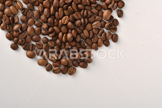 حبوب البن (بذرة نبات القهوة) نوع من أنواع المشروبات المنشطة ذهنياً , بذور البن المحمصة ,  بذور البن الطازجة الطبيعية  , خلفية بيضاء