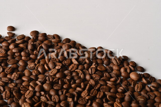 حبوب البن (بذرة نبات القهوة) نوع من أنواع المشروبات المنشطة ذهنياً , بذور البن المحمصة ,  بذور البن الطازجة الطبيعية  , خلفية بيضاء