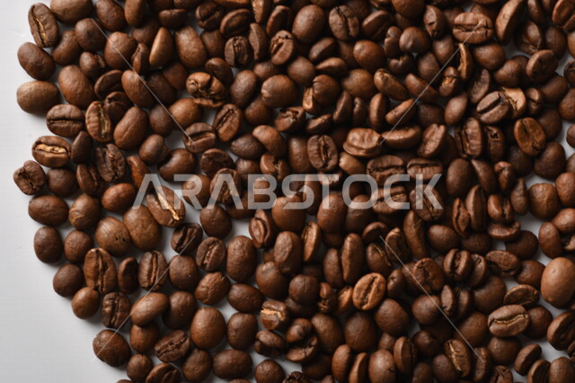 حبوب البن (بذرة نبات القهوة) نوع من أنواع المشروبات المنشطة ذهنياً , بذور البن المحمصة ,  بذور البن الطازجة الطبيعية  , خلفية بيضاء