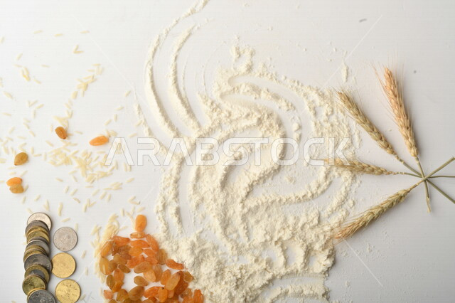 مجموعة من الأرز والزبيب والقمح والطحين والعملات المعدنية على خلفية بيضاء .