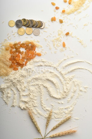 مجموعة من الأرز والزبيب والقمح والطحين والعملات المعدنية على خلفية بيضاء .