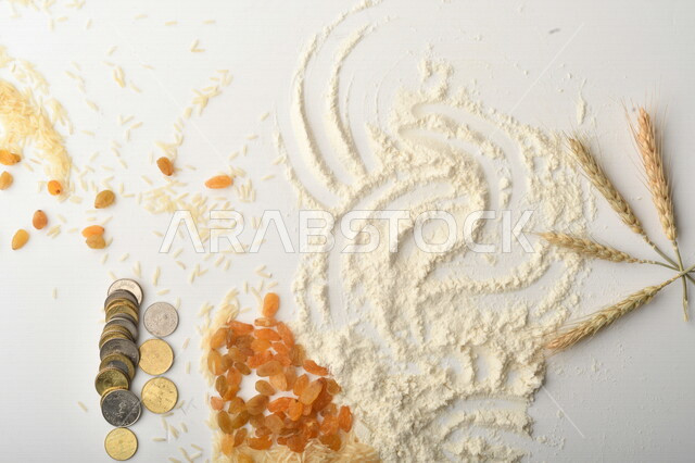 مجموعة من الأرز والزبيب والقمح والطحين والعملات المعدنية على خلفية بيضاء .