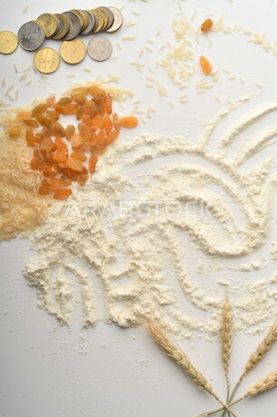 مجموعة من الأرز والزبيب والقمح والطحين والعملات المعدنية على خلفية بيضاء .