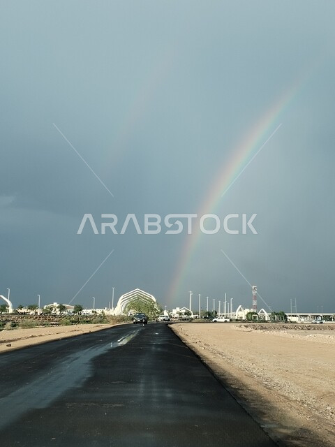 منظر سماء المدينة المنورة الملبدة بالغيوم السوداء الكبيرة، الأجواء الشتوية في المملكة العربية السعودية،   طرق المرور والسيارات الاسفلتية، النمو والتطور العمراني والحضاري، ظهور قوس قزح بألوانه الساحرة بعد هطول الأمطار