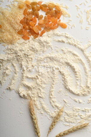 A bunch of rice, raisins and flour on a white background.