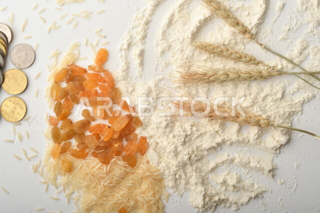 مجموعة من الأرز والزبيب والقمح والطحين والعملات المعدنية على خلفية بيضاء .