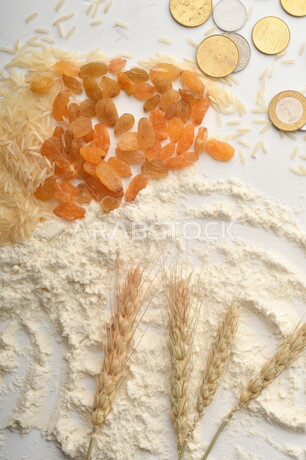 مجموعة من الأرز والزبيب والقمح والطحين والعملات المعدنية على خلفية بيضاء .